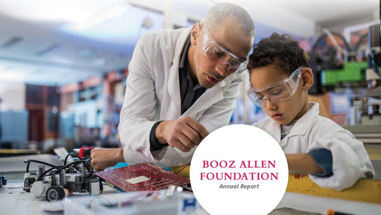 An African American man in a white lab coat teaching an African American child robotics circuitry