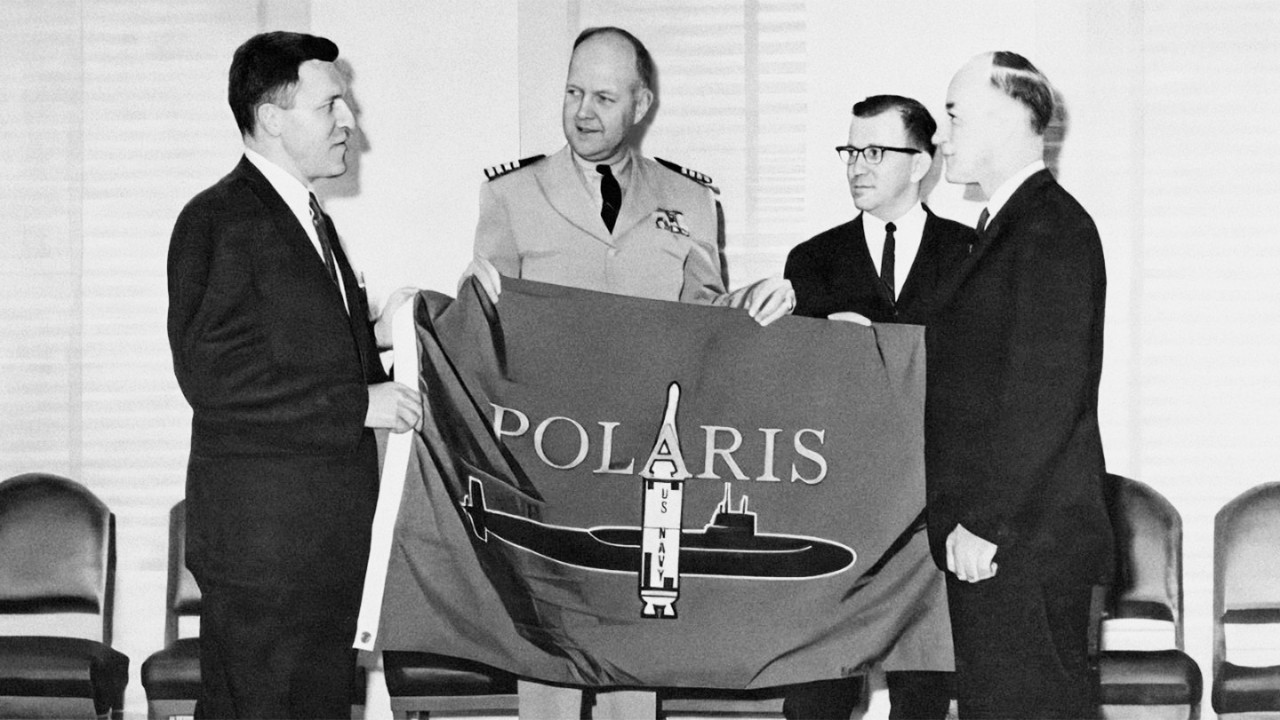 U.S. Navy Captain John Dudley (second from left) presents a Polaris flag to J.W. Pocock (left) and others in appreciation of BAARINC’s contributions